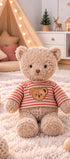 Peluche ours beige Colin de Bukowski Design assise sur un tapis, avec un haut rayé rouge et blanc orné d’une tête d’ours.