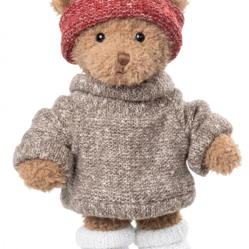 Peluche ours Matt de Bukowski Design vue de face sur fond blanc, en pull gris, bonnet rouge et chaussons blancs