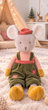 Peluche souris Henry de Bukowski Design assise sur un tapis dans une chambre d’enfant, en salopette verte et chapeau corail.