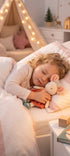 Une enfant endormie dans son lit serre contre elle la peluche souris Ingefrid de Bukowski Design, en jupe corail et nœud fleuri.